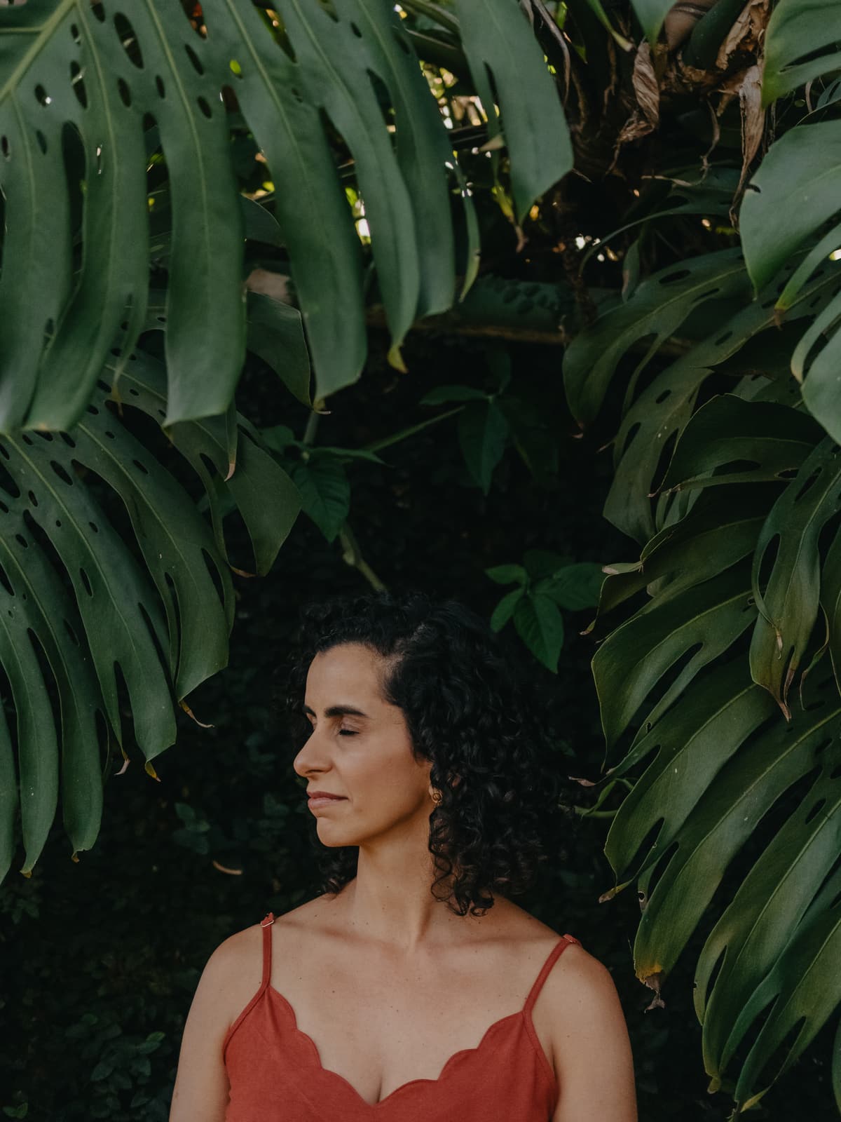 Lu Cerqueira em um jardim, de olhos fechados, em silêncio